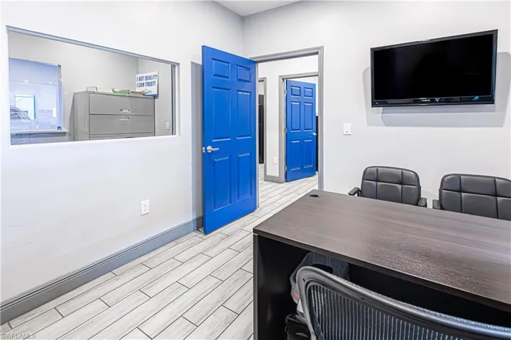 Recessed wall-mounted television, wood-finish flooring, vibrant blue paneled doors, and a built-in wall opening