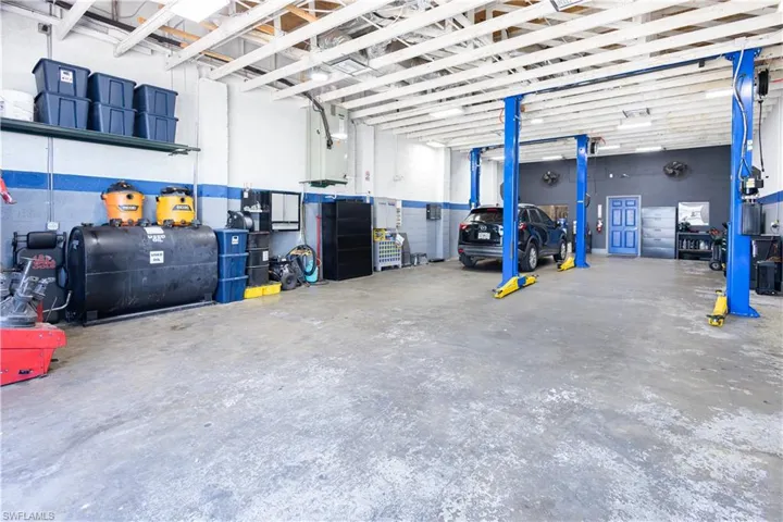 Concrete flooring, exposed ceiling joists, and a two-post vehicle lift system