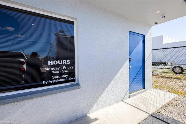 Commercial exterior with a blue entry door, window signage, and textured wall finish