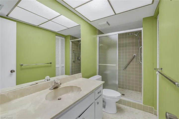 Primary bathroom with toilet, vanity, tile patterned flooring, and a walk in shower with a convenient glass door