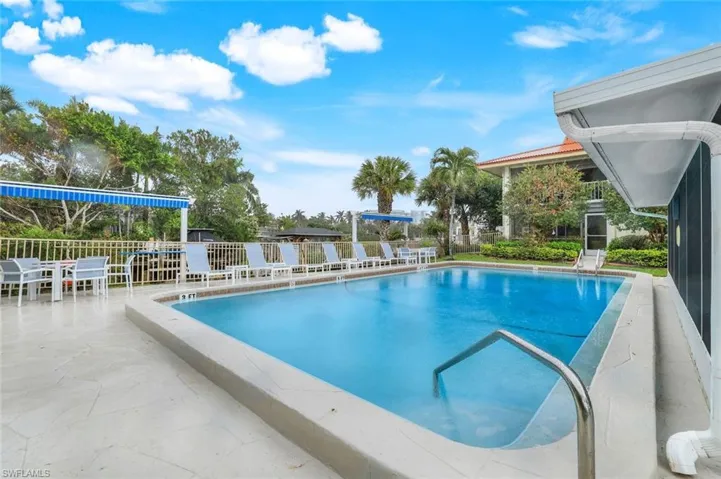 Community swimming pool featuring a patio area, community room, and custom awnings