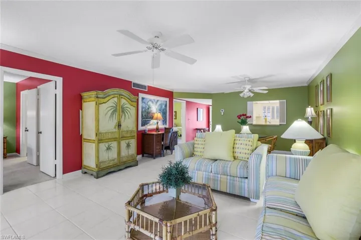 Living room featuring ornamental molding, ceiling fan, and light tile patterned flooring
