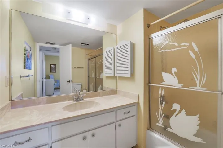 Full bathroom with toilet, vanity, and shower / bath combination with glass door
