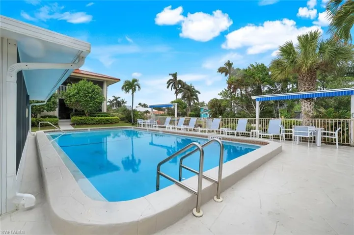 Community swimming pool featuring a patio area, community room, and custom awnings