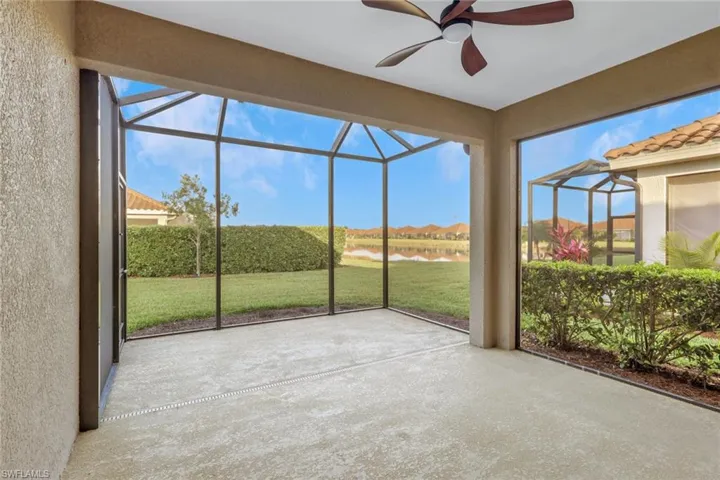 Unfurnished sunroom with a patio area, a water view, ceiling fan, and a residential view