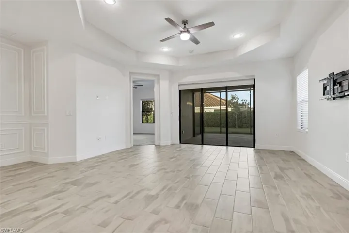 Spare room with plenty of natural light, a ceiling fan, wood tiled floors, a tray ceiling, and recessed lighting