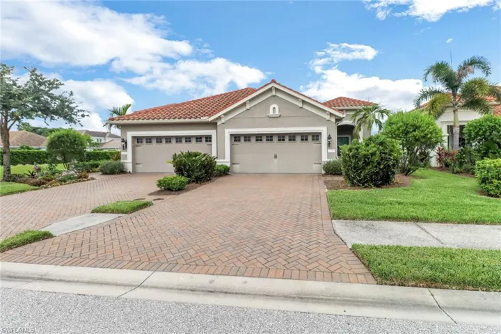 Mediterranean / spanish home with decorative driveway, a garage, stucco siding, a front lawn, and a tile roof