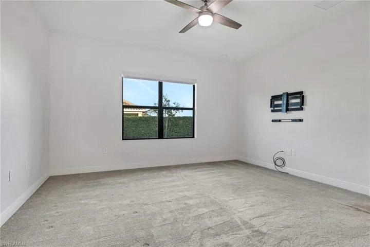 Empty room featuring light carpet and a ceiling fan