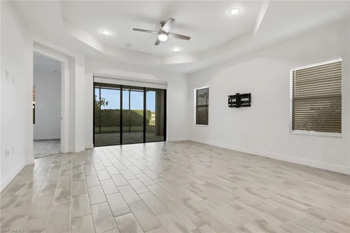Empty room with a ceiling fan, a tray ceiling, wood finish floors, and recessed lighting