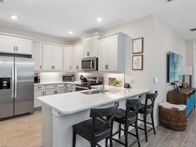 Kitchen with a peninsula, a breakfast bar, appliances with stainless steel finishes, light countertops, and light wood finished floors