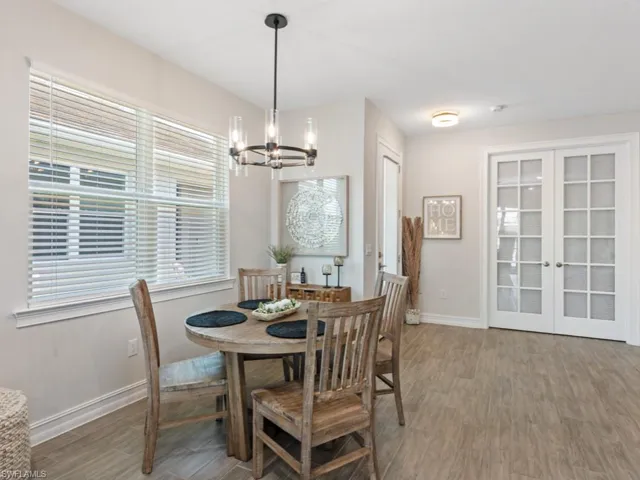 Dining area with french doors, wood finished floors, an inviting chandelier, and baseboards