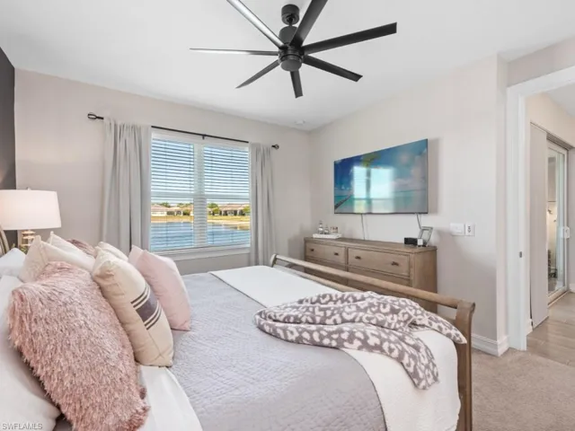 Bedroom featuring light carpet, baseboards, and a ceiling fan