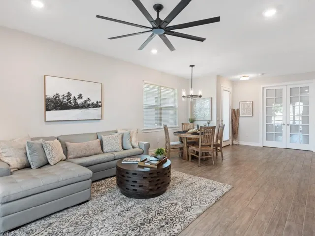 Living area with baseboards, recessed lighting, wood finished floors, and ceiling fan with notable chandelier