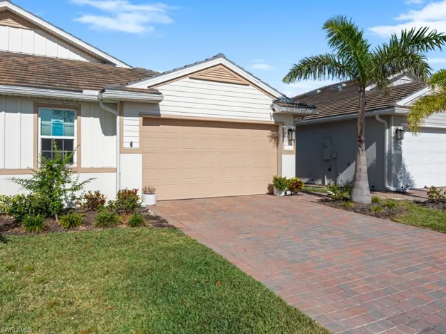 Single story home with board and batten siding, an attached garage, and decorative driveway
