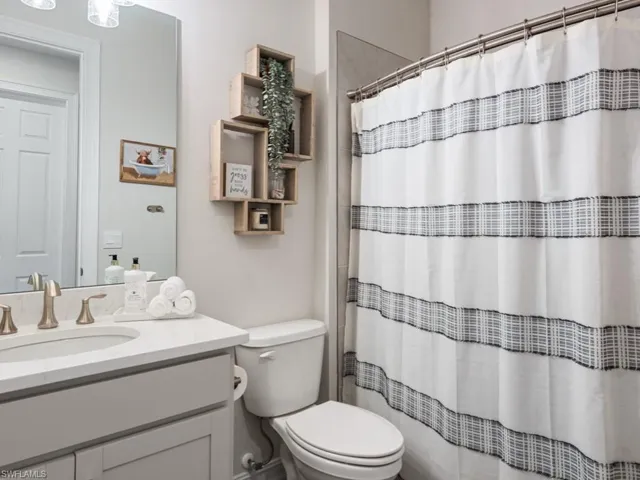 Full bath with toilet, vanity, and a shower with shower curtain