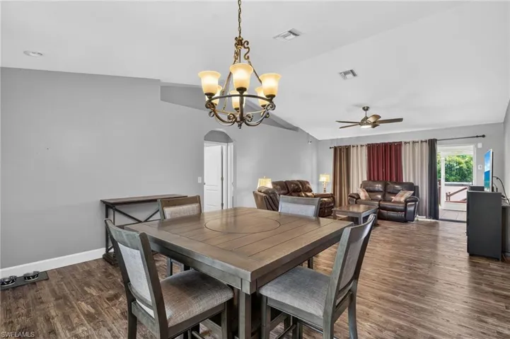 Open-concept living area with wood-finish flooring, vaulted ceilings, and recessed lighting