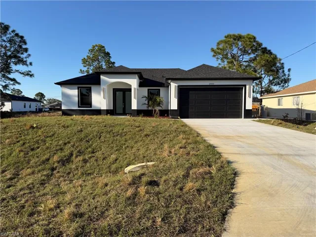 Ranch-style house featuring concrete driveway, an attached garage, a front lawn, and stucco siding
