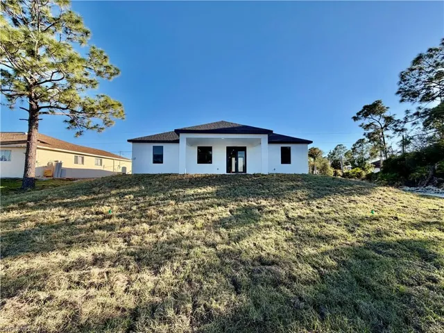 View of front of house featuring stucco siding and a front lawn
