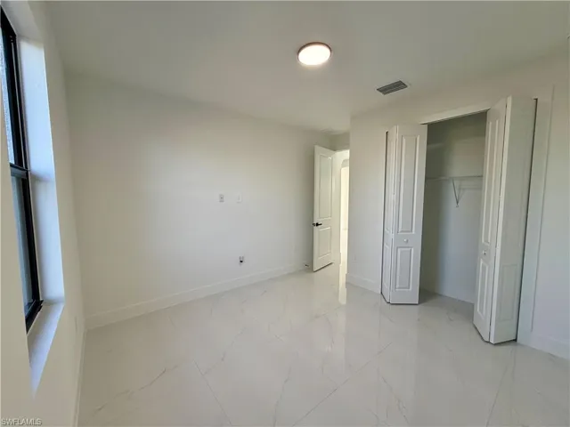 Unfurnished bedroom with a closet and light marble finish floors