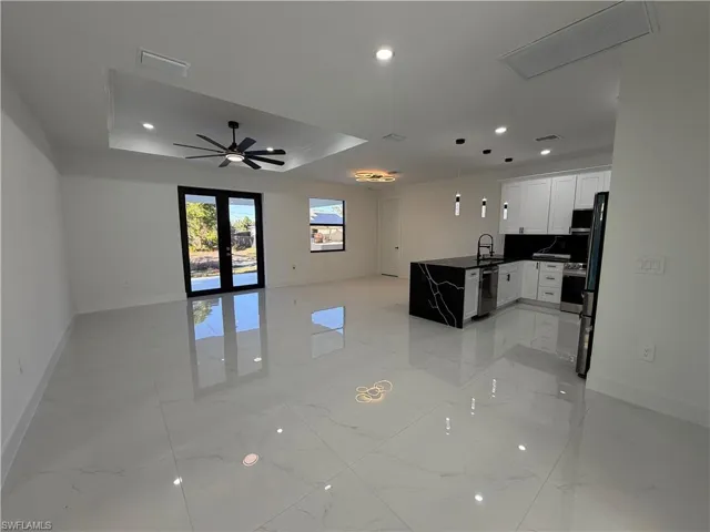 Kitchen featuring a peninsula, open floor plan, white cabinets, a raised ceiling, and pendant lighting