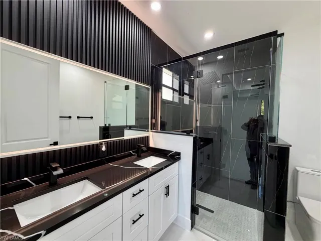 Full bath with double vanity, a stall shower, and recessed lighting