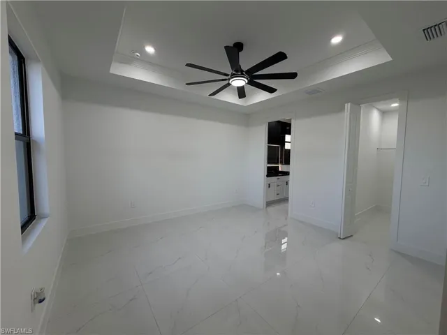 Unfurnished bedroom with a spacious closet, recessed lighting, a ceiling fan, light marble finish floors, and ornamental molding