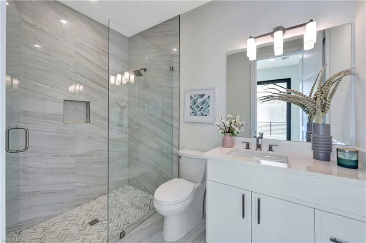 Bathroom featuring a marble finish shower and vanity