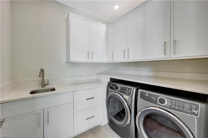 Laundry area with washing machine and clothes dryer, cabinet space, light wood-style floors, and recessed lighting
