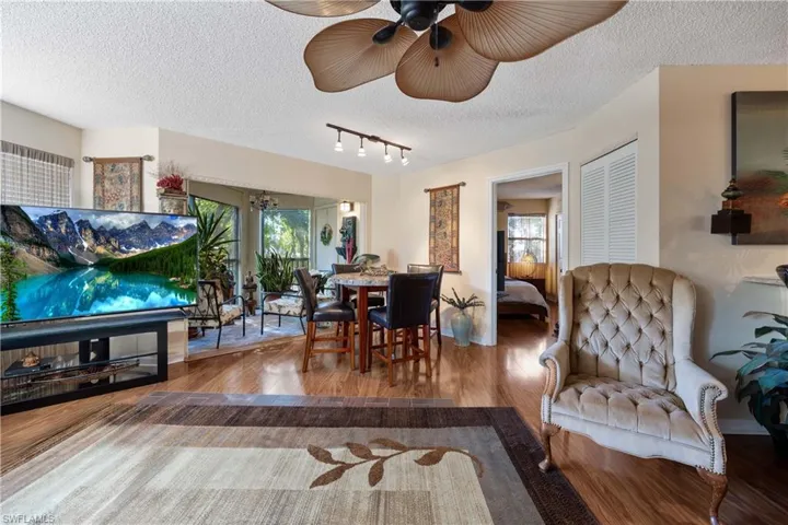 Living room featuring rail lighting, ceiling fan, wood-type flooring, and a textured ceiling