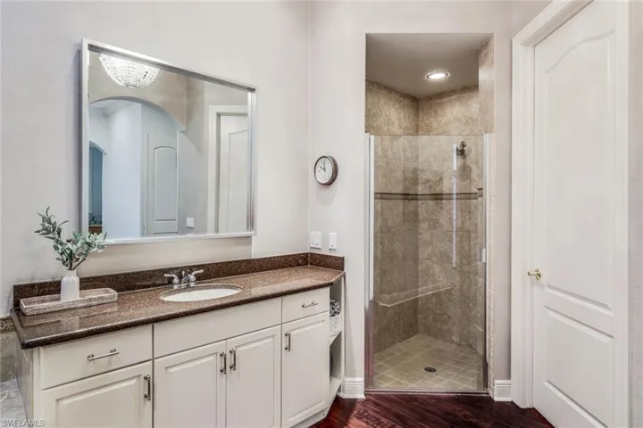Bathroom featuring tiled shower, wood-type flooring, and vanity with extensive cabinet space
