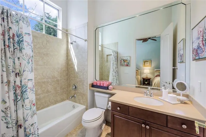 Full bathroom with shower / bath combo with shower curtain, tile floors, vanity with extensive cabinet space, ceiling fan, and toilet