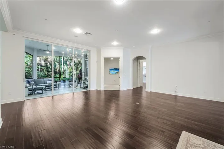 Unfurnished room with a notable chandelier, dark wood-type flooring, and crown molding