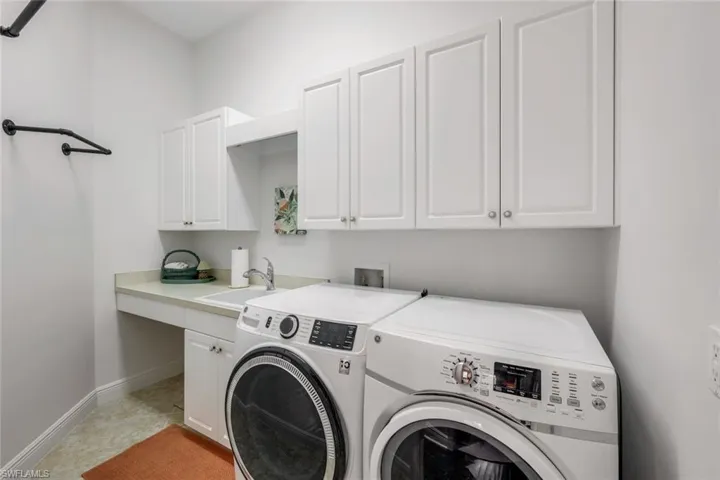 Laundry area featuring independent washer and dryer, cabinets, washer hookup, sink, and light tile floors