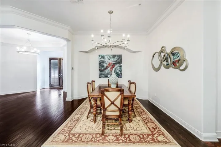 Dining area featuring crown molding, a chandelier, and dark wood-type flooring