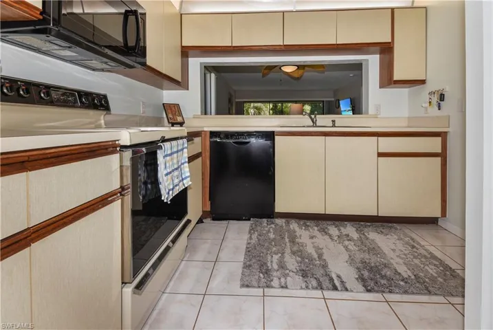 Kitchen featuring black appliances, light countertops, and light tile patterned flooring
