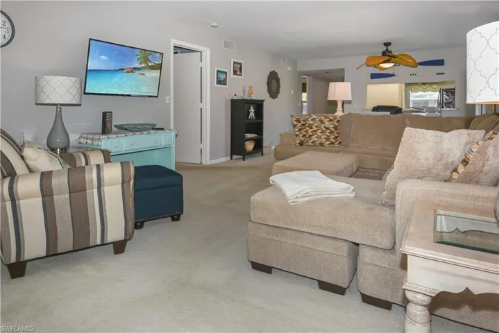 Living area with ceiling fan and light colored carpet