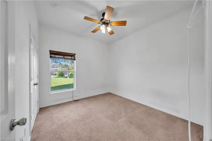 Carpeted empty room with a ceiling fan and baseboards