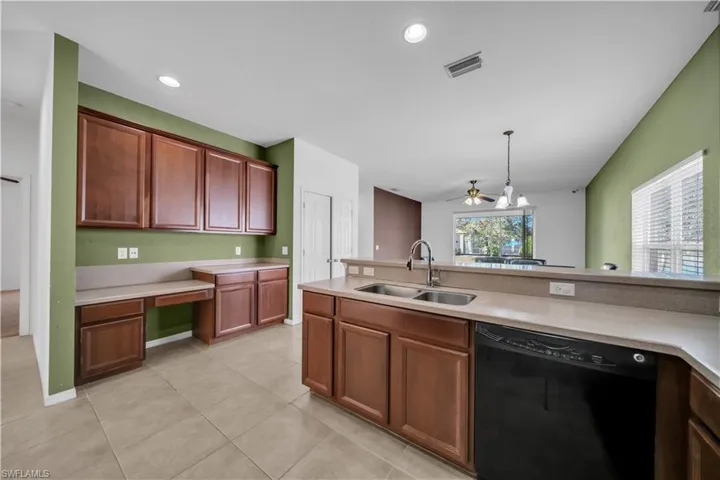 Kitchen featuring black dishwasher, built in study area, hanging light fixtures, recessed lighting, and light tile patterned floors