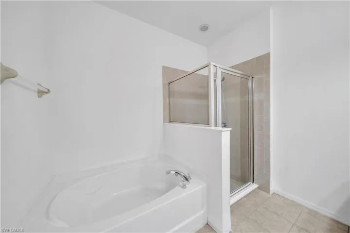 Bathroom featuring a garden tub, a stall shower, and light tile patterned floors