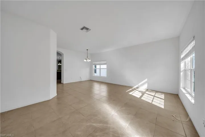 Unfurnished room with arched walkways, a chandelier, and light tile patterned flooring