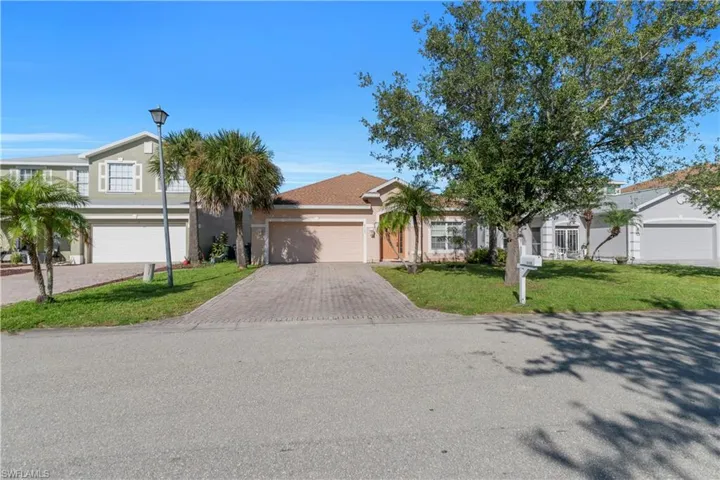 View of front facade with decorative driveway, a front yard, stucco siding, and a garage