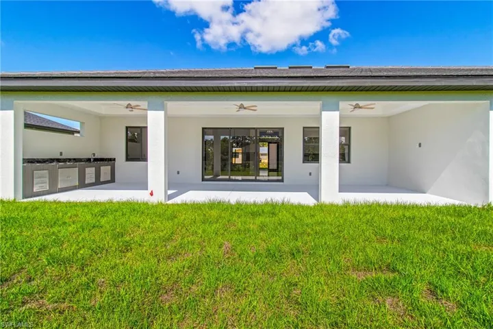 Rear view of house featuring ceiling fan, a patio, stucco siding, and a lawn