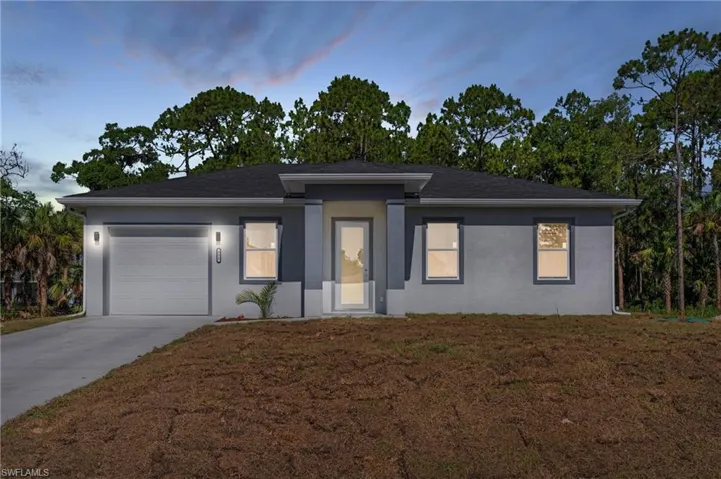 View of front facade featuring a garage and a yard