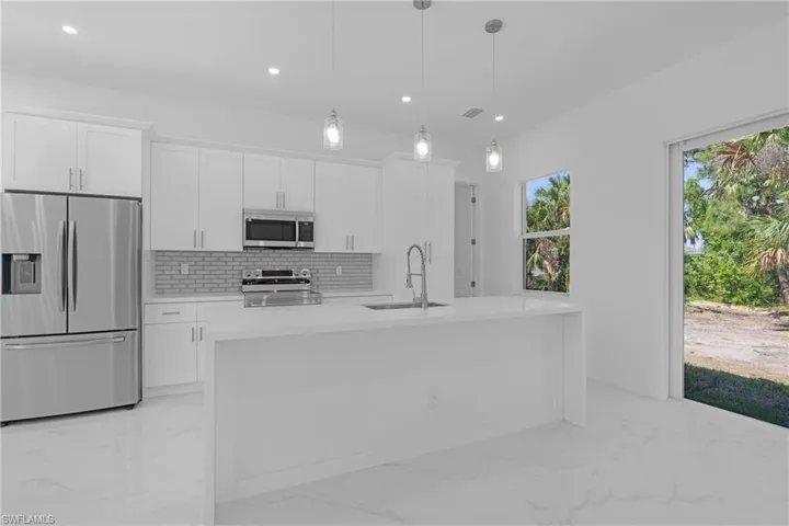 Kitchen with appliances with stainless steel finishes, white cabinets, and light tile floors