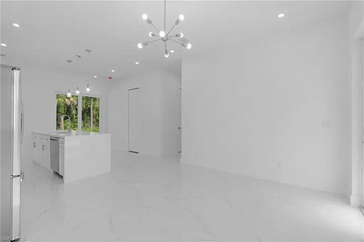 Tiled empty room featuring a chandelier and sink