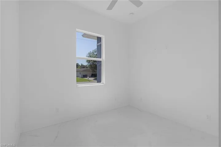 Tiled spare room featuring ceiling fan