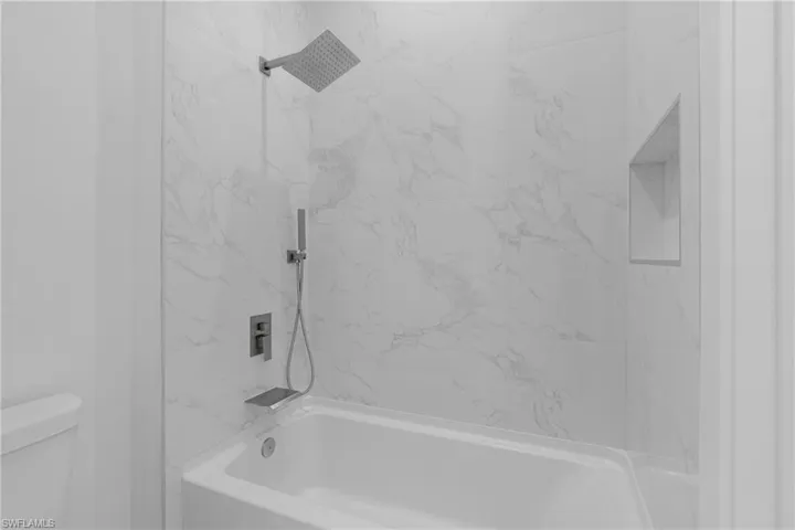 Bathroom featuring tiled shower / bath and toilet