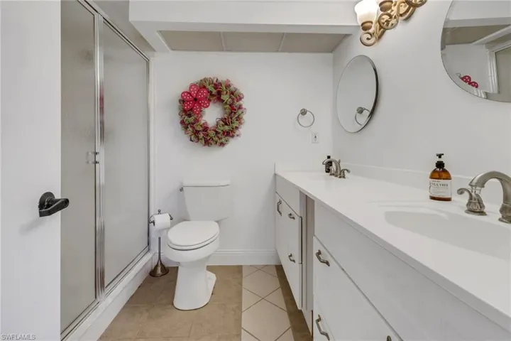 Bathroom featuring walk in shower, vanity, tile patterned flooring, and toilet