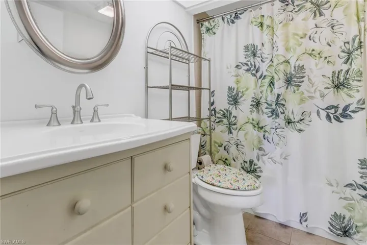Bathroom featuring walk in shower, vanity, toilet, and tile patterned floors