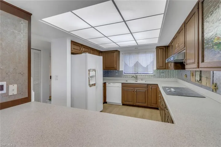 Kitchen featuring backsplash, white appliances, sink, and light hardwood / wood-style flooring
